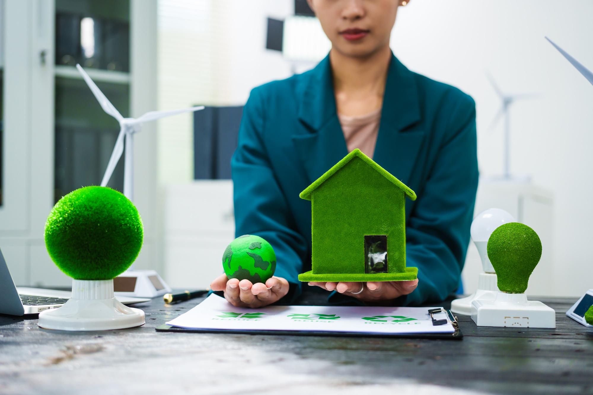 An Asian businesswoman sits at her desk, discussing clean energy solutions their impact on homes