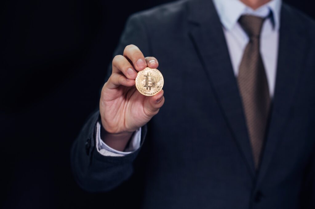 Close-up of businessman showing and holding bitcoin sign of coin