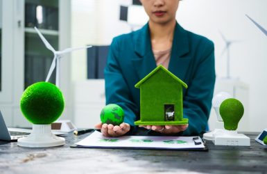 An Asian businesswoman sits at her desk, discussing clean energy solutions their impact on homes